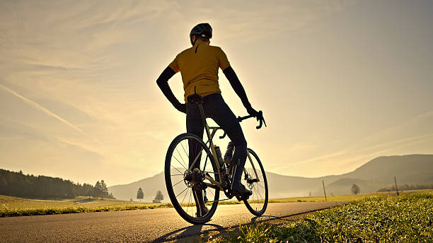 istock Cyclist pauses on scenic road at sunset 2219475429