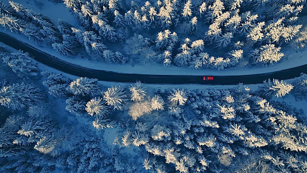 istock Red Car Travels on Snowy Road 2219476646