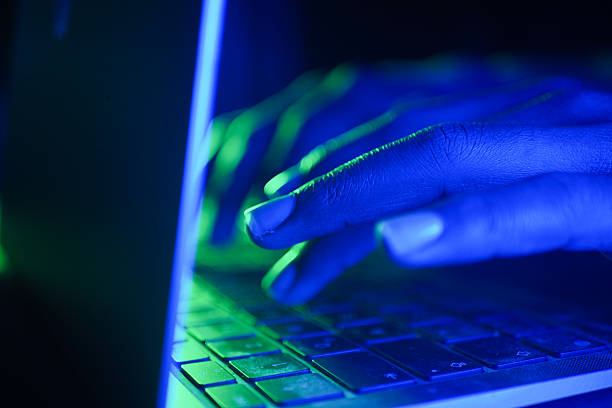 istock Hacker Hands typing on a laptop illuminated by blue and green lights 2219480010