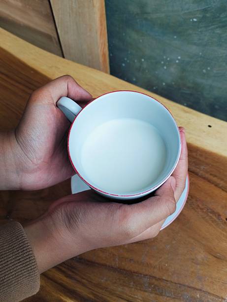 istock Cozy Drink Moment Hand Grasping Milk Cup on Wood Surface 2219481329