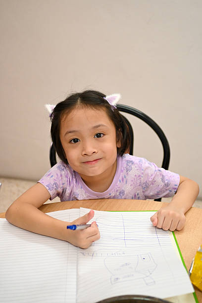 Asian little Chinese girl writing homework at home