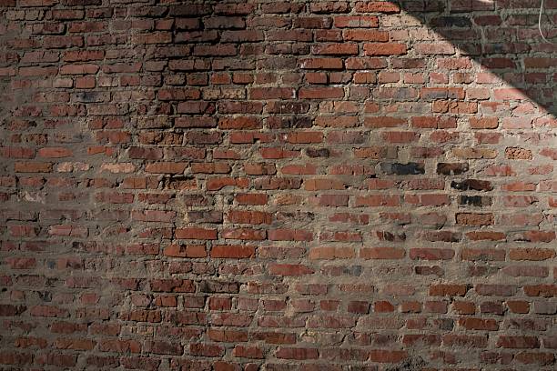 istock Old red brick wall with rough texture and shadow. Rustic urban background for design or construction themes. 2219482052