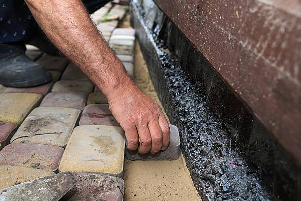istock Laying paving stones by hand next to a foundation coated with waterproofing 2219482457