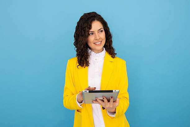 istock Professional businesswoman smiling, working on digital tablet against blue backdrop 2219484522