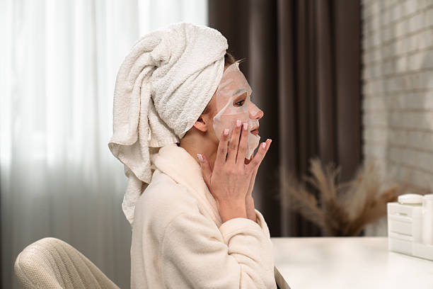 istock Woman Applying Sheet Mask for Relaxing Skincare Routine 2219485449