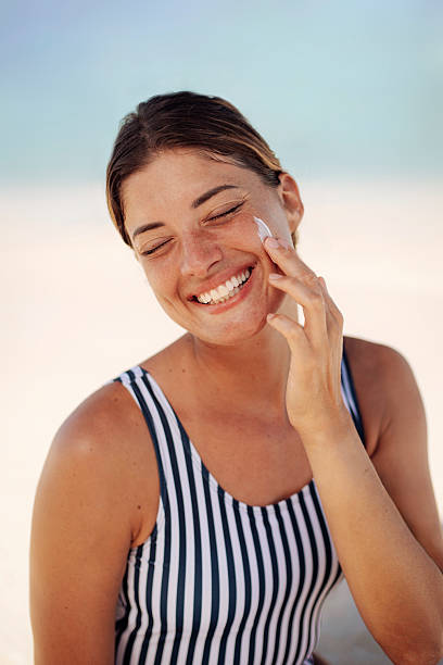 istock Smiling Woman Applying Sunscreen on Sunny Beach 2219487562