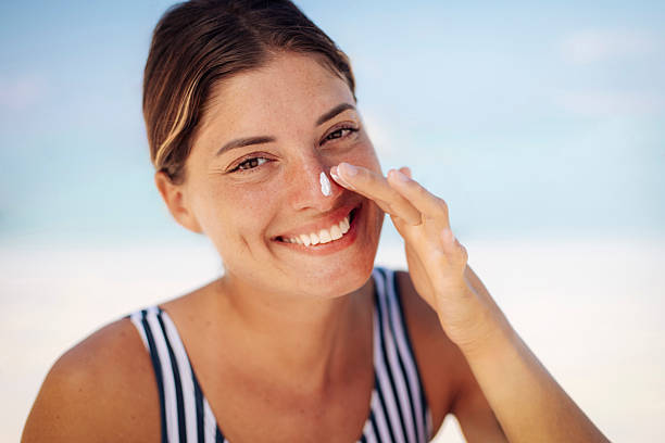 istock Smiling Woman Applying Sunscreen at Sunny Beach 2219487688