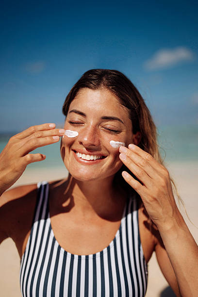istock Smiling Woman Applying Sunscreen on Sunny Beach 2219488598