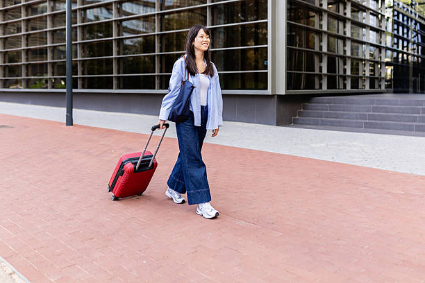 istock Young asian businesswoman pulling luggage and walking on sidewalk 2219488986