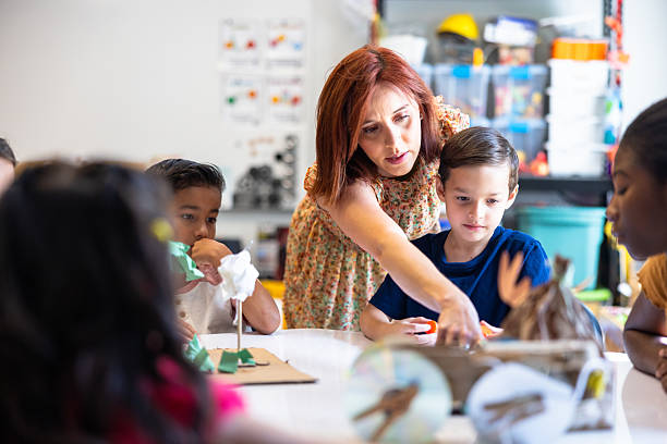 istock Teacher interacting with a small group of students at a round table in a classroom 2219489338
