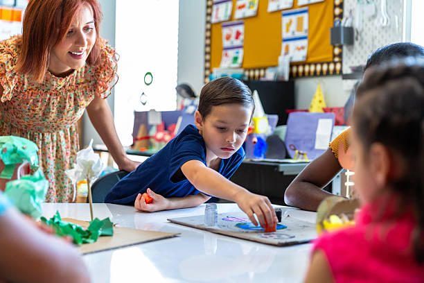 istock Teacher interacting with a small group of students at a round table in a classroom 2219489351