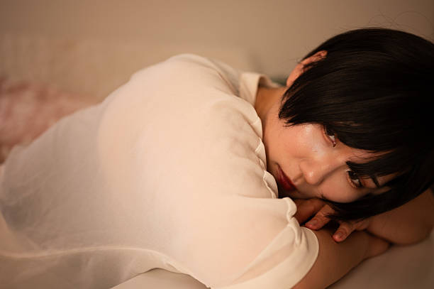 istock Young Asian woman lying face down on a table and looking outside 2219490101