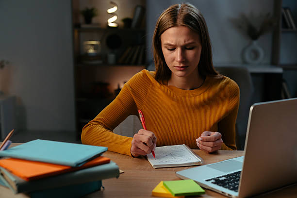 istock Woman Writing Notes at Desk with Laptop in Cozy Office Environment 2219490244