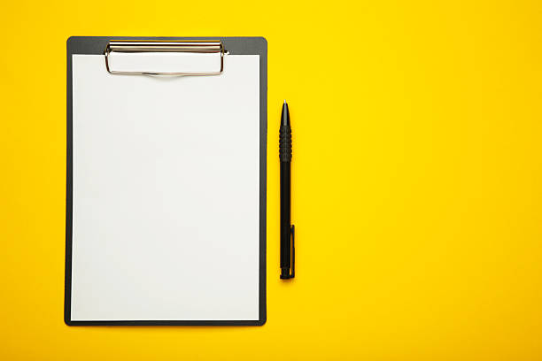 istock Black tablet with piece of empty paper and pen on yellow background. Space for text 2219491698