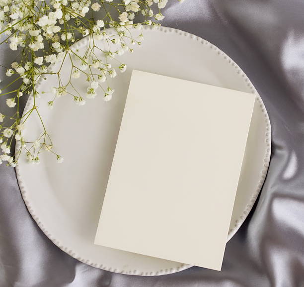 istock Greeting card mockup, menu blank mock up, wedding card, wedding invitation on table place setting ,white flowers  frame on grey silk background top view. 2219491752