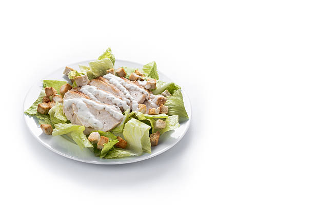 A fresh and crunchy Caesar salad made with crisp romaine lettuce, creamy Caesar dressing, crunchy croutons isolated on white background