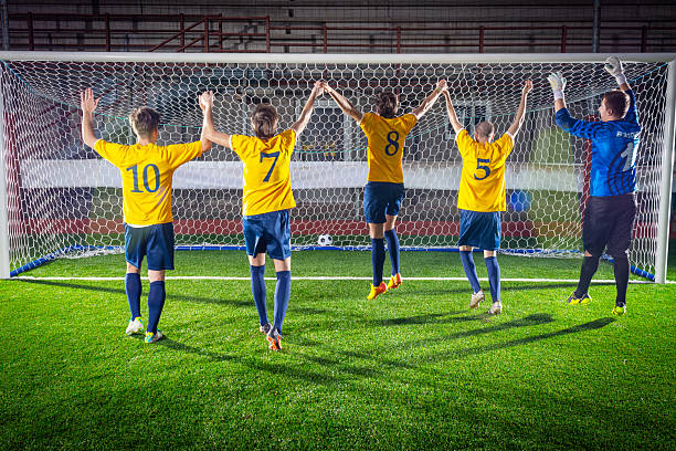Male football players defending while playing match on football pitch.