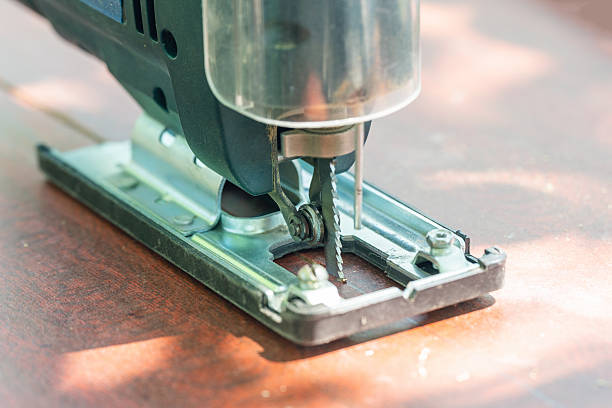 A carpenter cuts a board with an electric jigsaw.