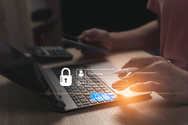 istock Concept of logging into online website on laptop using personal username and password to prevent fraud and for cyber security. Businessman sitting working in a room with only one illuminated spot. 2219493815