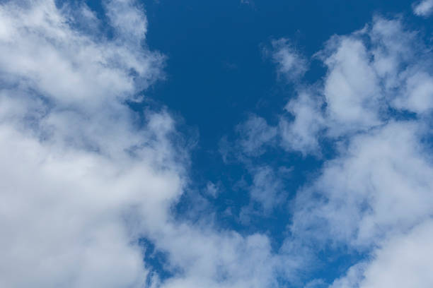 A serene view of fluffy white clouds scattered across a vibrant blue sky, creating a peaceful and tranquil atmosphereâperfect for nature, weather, or background themes.