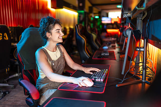istock Young woman playing video games in internet cafe 2219497039