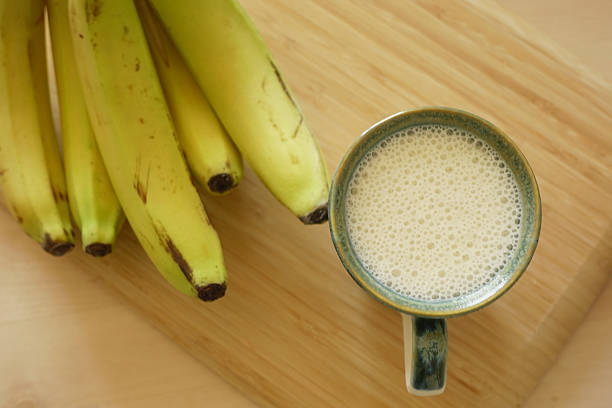 Ripe bananas arranged beside a creamy smoothie in a mug.