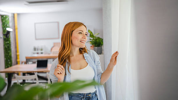 istock Portrait of redhead smile while look through window at home 2219502166