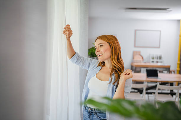 istock Portrait of redhead smile while look through window at home 2219502237