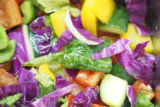 Fresh vegetables including bell peppers and cabbage are chopped together.