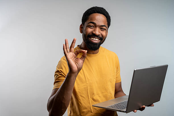 istock Successful young black freelancer showing okay gesture with laptop isolated over grey background 2219505264