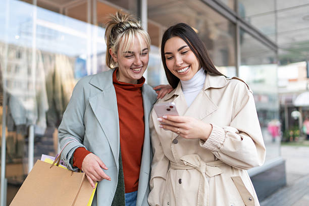 istock Two young women sharing a laugh while shopping and using a smartphone 2219506488