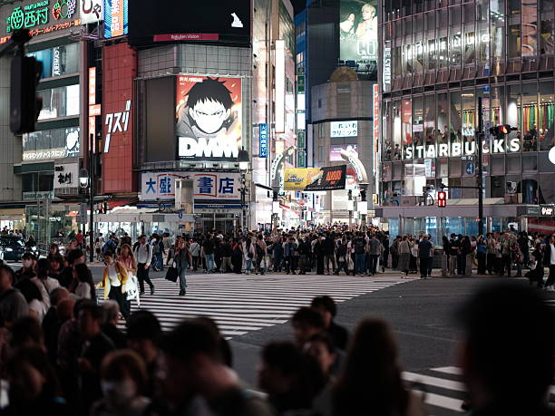 Shot in Tokyo, Japan, this angled view of Shibuya Crossing captures the ebb and flow of a bustling crowd beneath neon signage. Perfect for editorial content on commuter life, street photography, or metropolitan energy.
