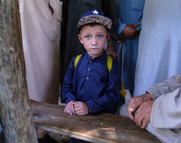 Afghan child waiting with backpack and cap in a crowd
