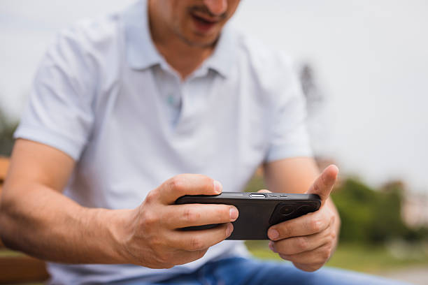 Male gamer using smart phone when resting in a park