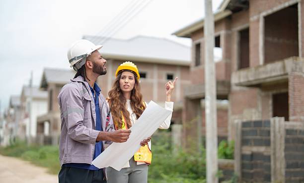 istock Two construction supervisors review blueprints while pointing out details of buildings in progress in an urban neighborhood. 2219513341