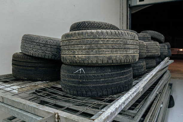 Several stacks of used car tires rest on metal racks inside a clean, modern garage. The worn treads and organized storage suggest a professional automotive environment.