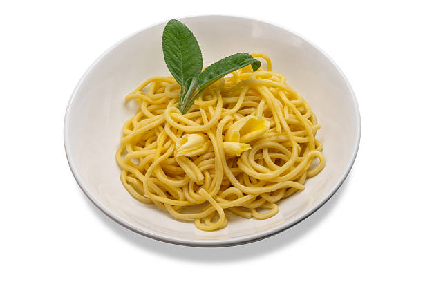 Egg noodles topped with butter and sage in white dish with butter slices and sage leaves, tagliolini in white dish isolated on white with clipping path included