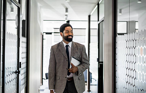 istock Smiling businessman walking through modern office corridor 2219516306