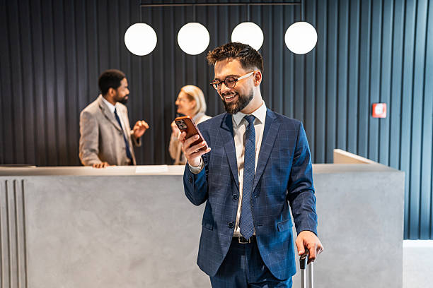 istock Smiling businessman using smartphone in hotel lobby while waiting at reception 2219516457