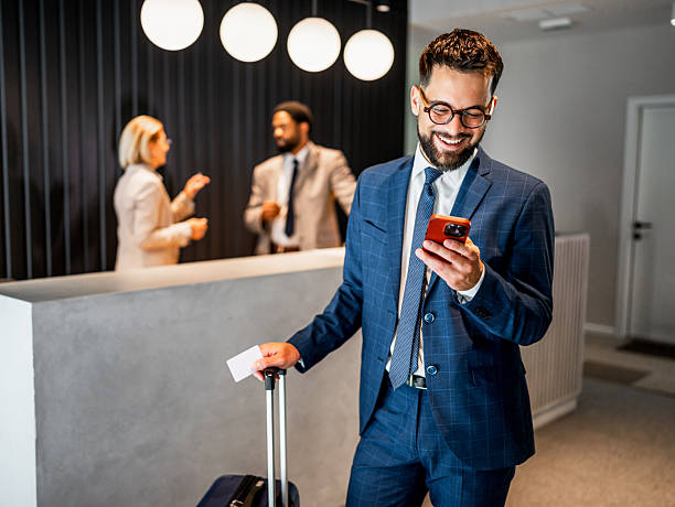 istock Businessman using smartphone in hotel lobby while waiting at reception 2219516625