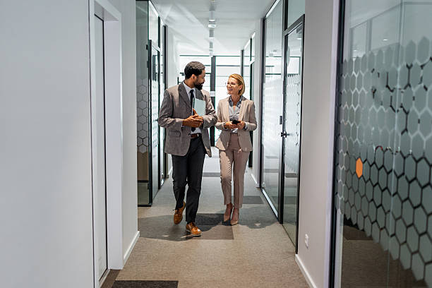 istock Businesspeople walking and talking in office hallway 2219516775