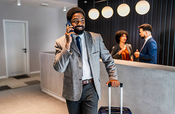 istock Businessman making a phone call while pulling luggage in hotel lobby 2219517085