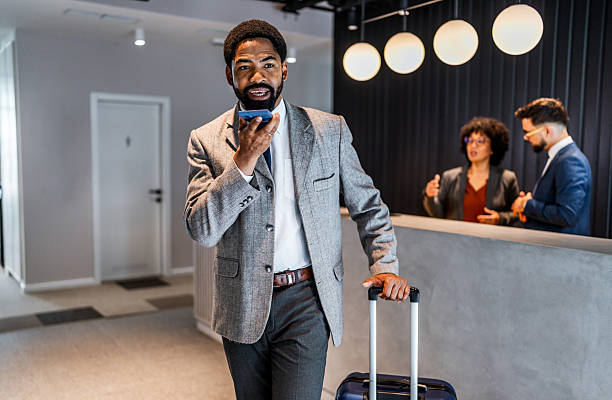 istock Businessman using smartphone while walking in hotel lobby with luggage 2219517109