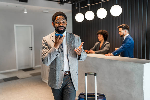 istock Businessman using smartphone while walking in hotel lobby with luggage 2219517223