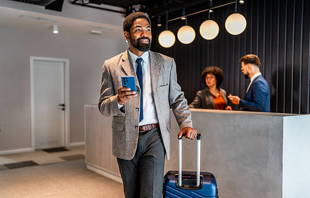 istock Businessman checking phone in hotel lobby 2219517350