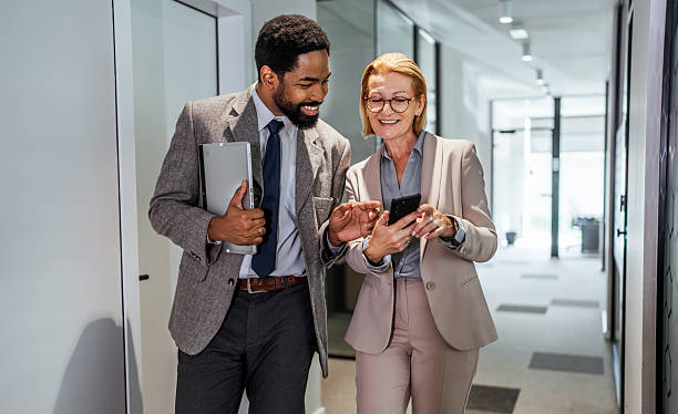 istock Business colleagues walking and using smartphone in office corridor 2219517688