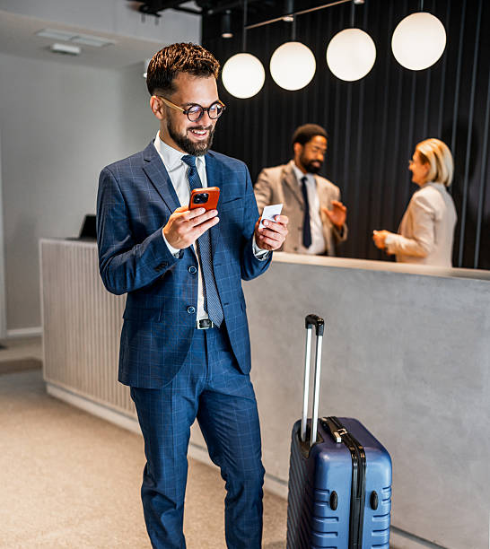 istock Businessman using smartphone in hotel lobby while waiting at reception 2219517959