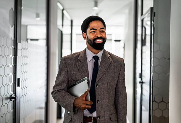 istock Smiling businessman walking through office hallway holding tablet 2219518881