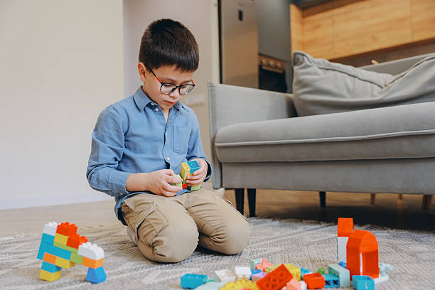 istock Little Boy with Glasses Playing with Building Blocks at Home 2219519121