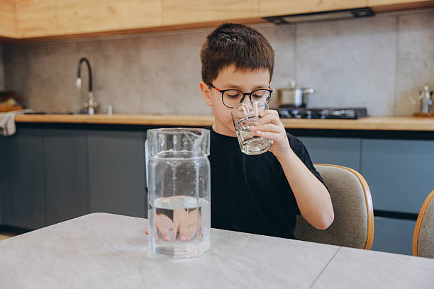 istock Child drinking fresh water from a glass in the kitchen 2219519297
